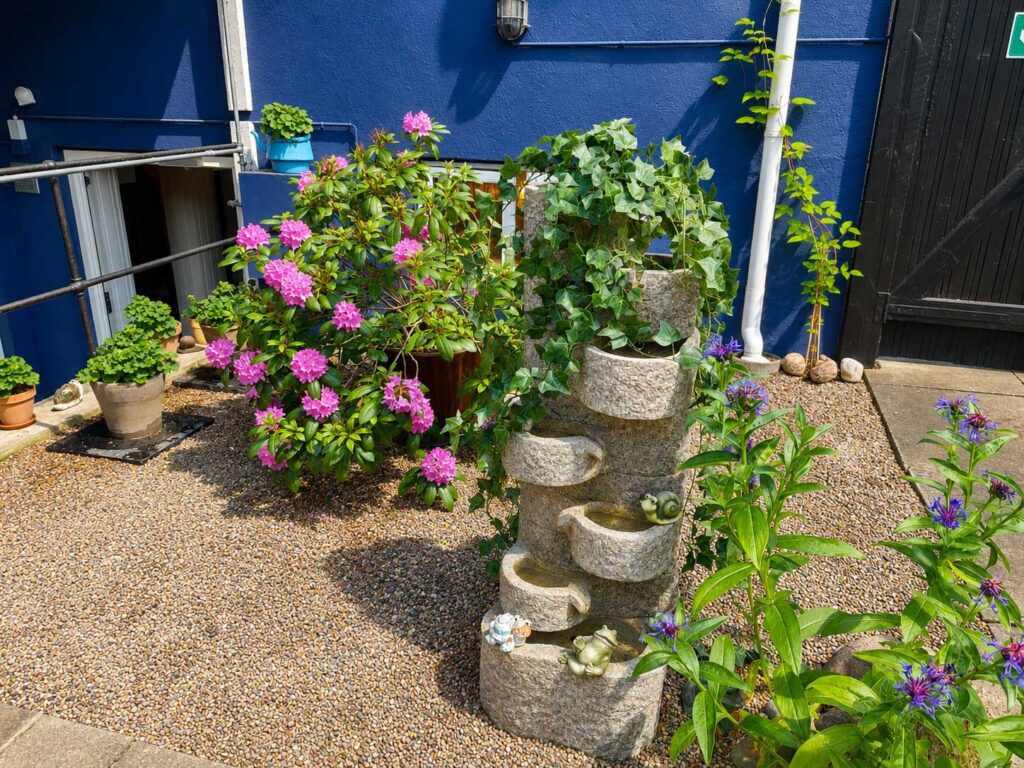 Beautiful courtyard garden with ornamental fountain, flowering shrubs and decorative planting in a peaceful setting.