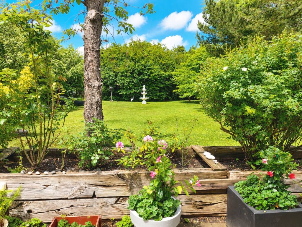 Secluded landscaped garden with open lawn, mature greenery, several varieties of apple trees, plum trees and a decorative fountain.