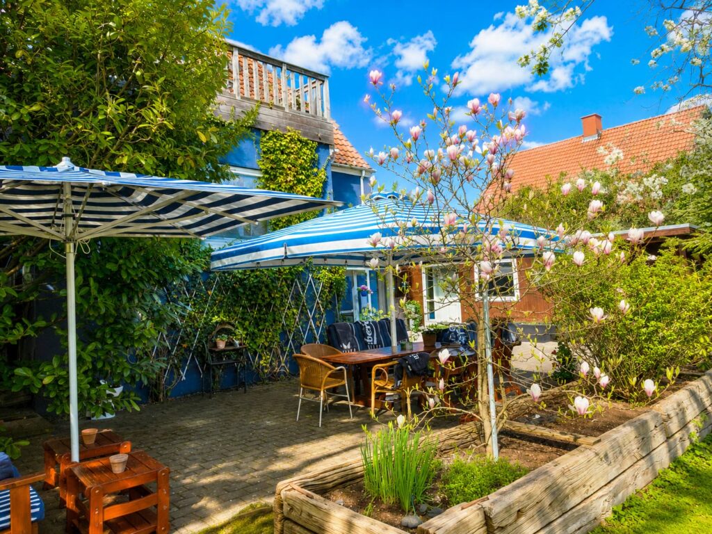 Spacious private garden terrace with a premium parasol featuring integrated lighting and heating, surrounded by lush greenery.