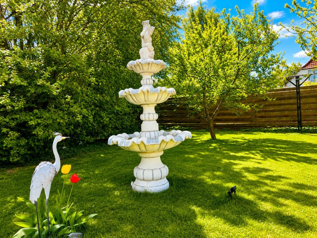 Decorative fountain set within the private garden, surrounded by mature greenery, apple trees and plum trees.